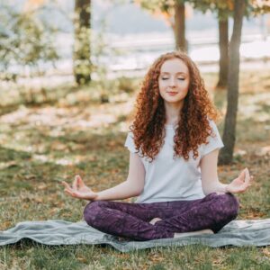 Woman meditating in a serene park during springtime, fostering relaxation and mental wellness.