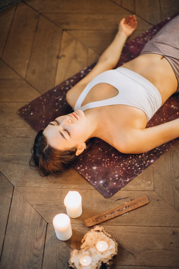 Woman practicing relaxation yoga with candles set for a calming atmosphere.